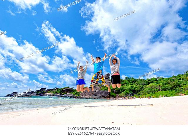 Family travels on vacation jumping with happy on beach near the sea under blue sky and clouds of summer at Koh Similan Island in Mu Ko Similan National Park