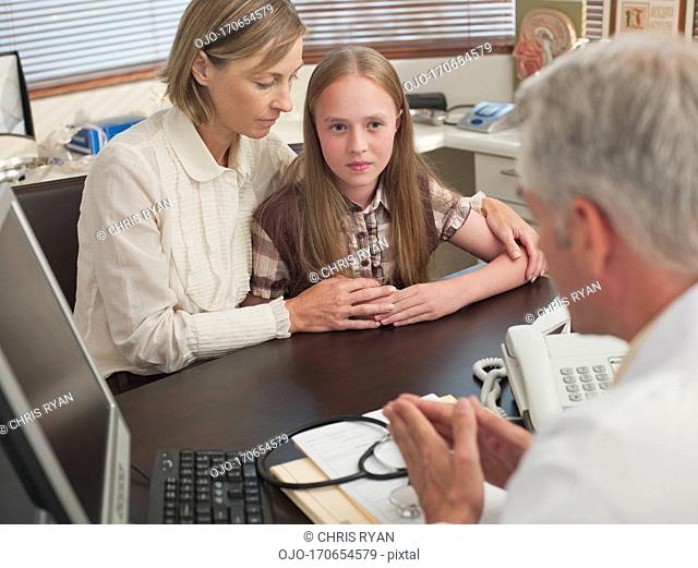 Doctor talking with mother and daughter in office