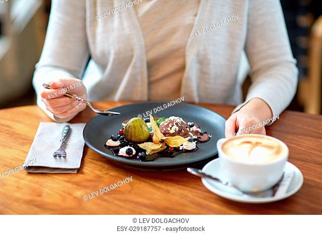 food, new nordic cuisine and people concept - woman eating chocolate ice cream dessert with blueberry kissel, honey baked fig and greek yoghurt with coffee at...