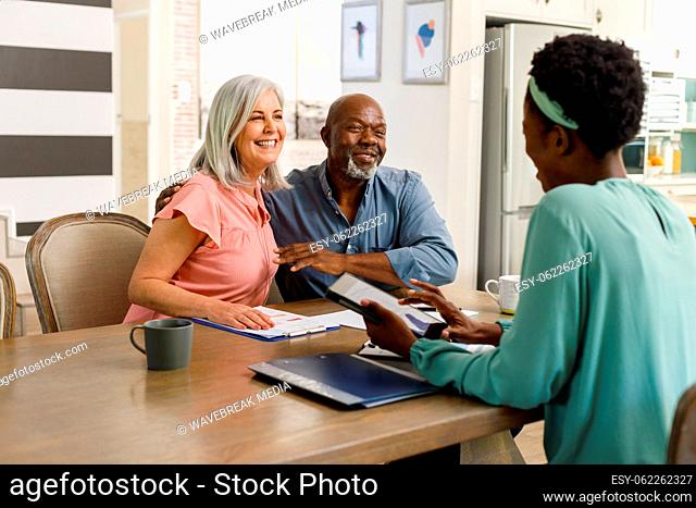 Happy senior diverse couple talking with african american female financial advisor
