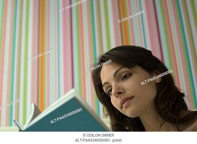 Young woman reading book, low angle view