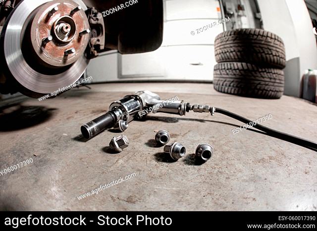 air gun to tighten a tire bolts on a suspended car at an auto shop