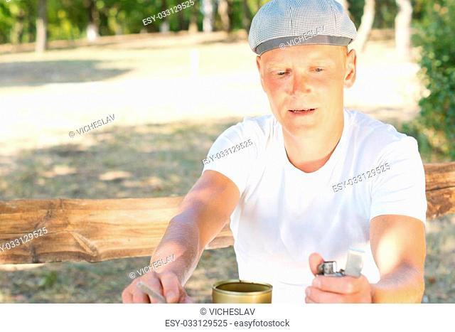 Middle-aged man about to light a cigarette concentrating on flicking his lighter to get a flame