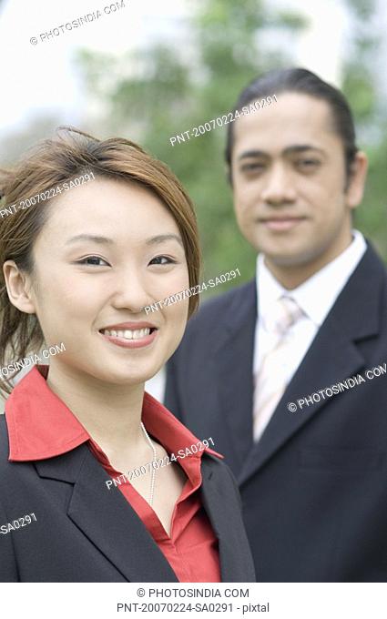Portrait of a businesswoman smiling with a businessman standing beside her
