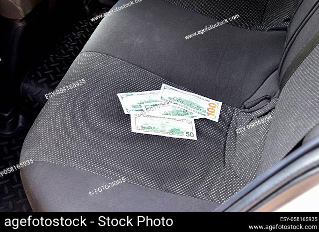 Several banknotes American dollars lie on the car seat. The money in the car