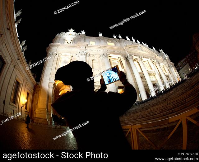 Wide angle shot of a woman silhouette using tablet computer to take photo or make video of Altar of Fatherland in Rome. Illuminated historic building
