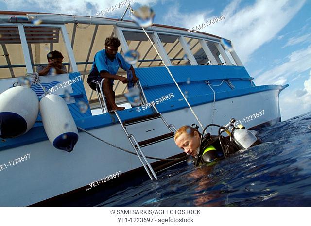 One scuba diver climbing aboard a diving boat, Kaafu Atoll, Maldive Islands