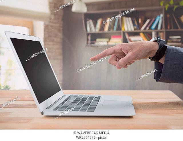 Businessman pointing at laptop with bookshelf
