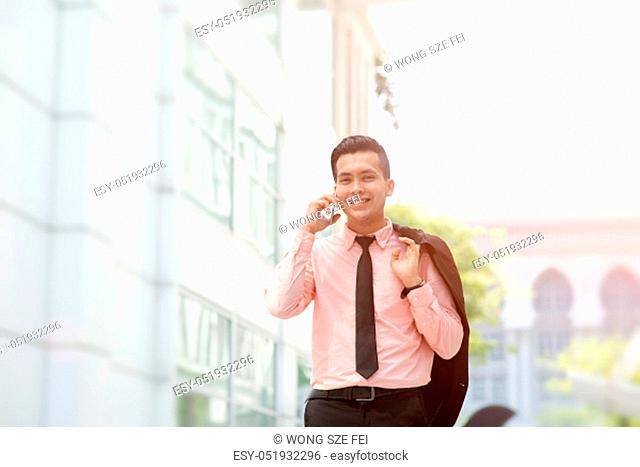 Young entrepreneur talking on the phone, walking on city street