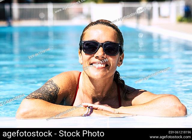 Cheerful middle age pretty lady smile and enjoy the blue pool water in summer holoiday vacation at home or hotel resort - concept of travel and active lifestyle...