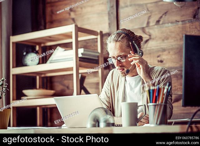Freelancer at working process using headphones and microphone. Man negotiating online via headphones