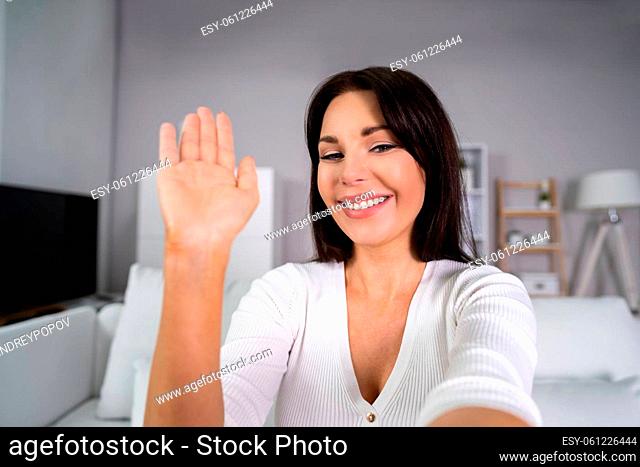 Portrait Of Happy Young Woman Waving At Home
