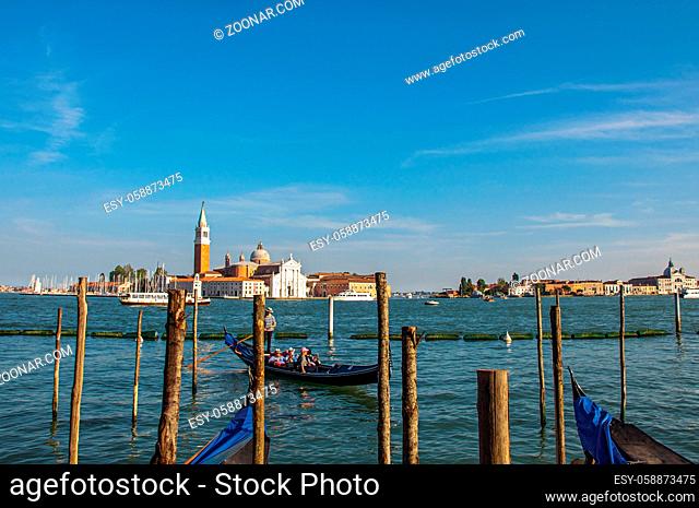 Venice, Italy - May 09, 2013. Panoramic view of Venice lagoon with pier and gondola in front and buildings behind. At the city of Venice