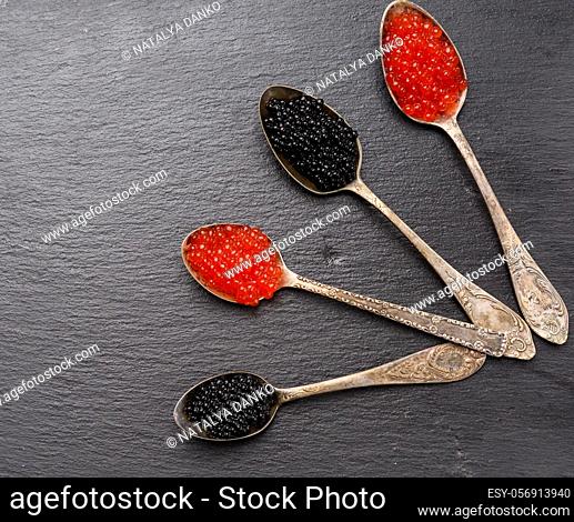 black caviar of paddlefish fish and red chum salmon caviar in a spoon, black background, top view