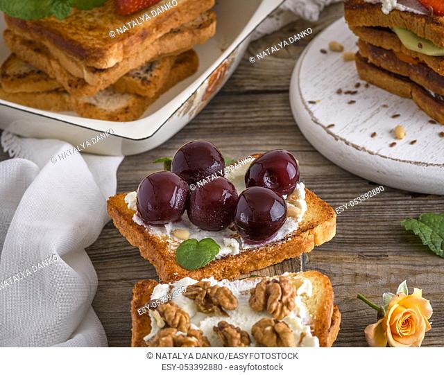 toast with mild cottage cheese and cherry berries on a gray wooden background, top view
