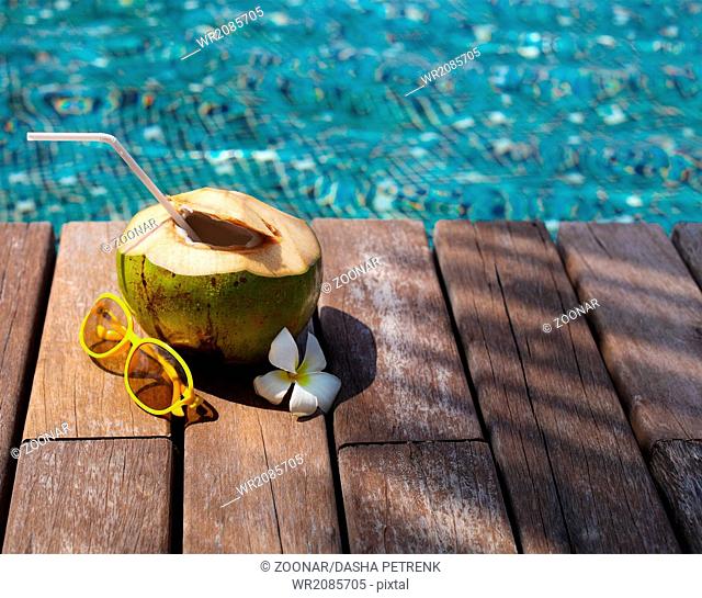 Coconut cocktail with drinking straw by the swimming pool