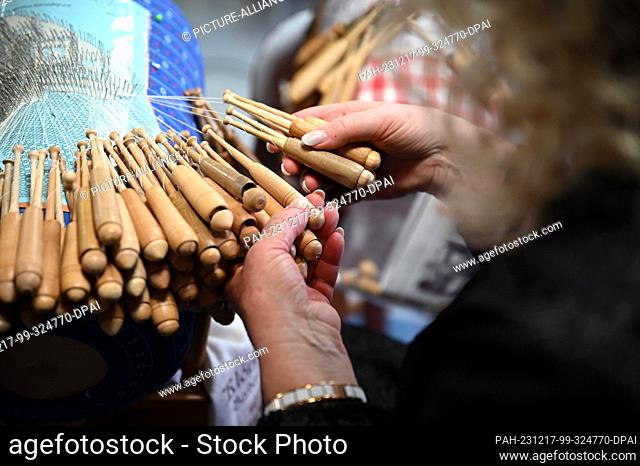 PRODUCTION - 21 November 2023, Saxony, Annaberg-Buchholz: Daniela Böhme twirls the wooden bobbins in her hands. There is evidence that bobbin lace has been made...