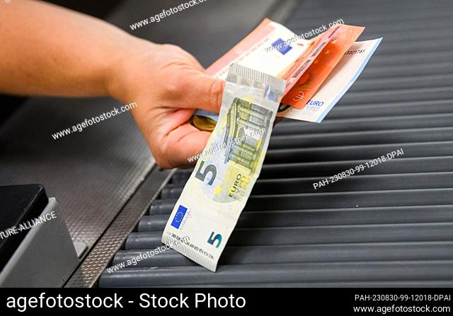 30 August 2023, Lower Saxony, Hanover: A customer holds change at the checkout of a supermarket. The Federal Statistical Office announces the inflation rate for...