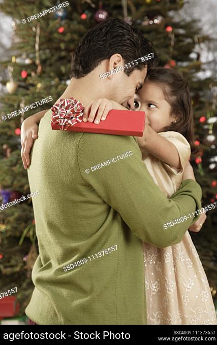 Hispanic father and daughter hugging on Christmas