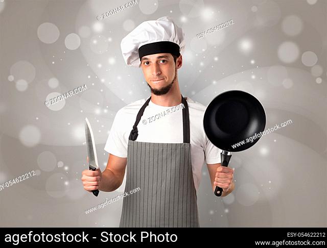 Male cook with kitchen tools and shiny grey wallpaper