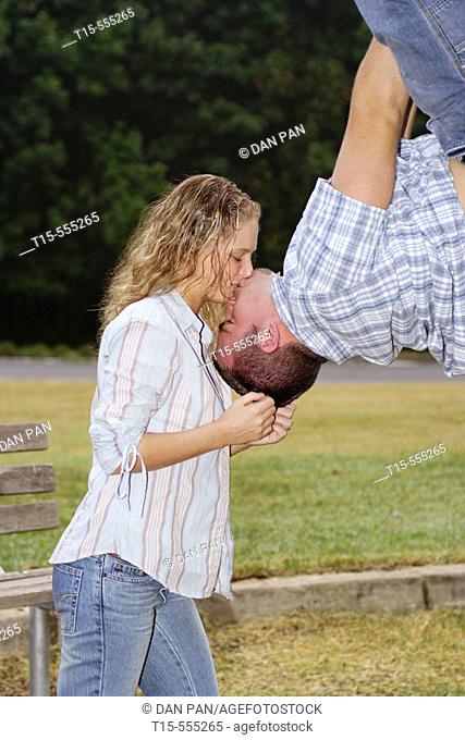 Couple in their 20's kissing with him hanging upside down