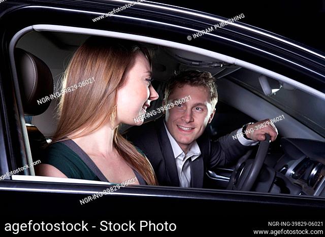 Young smiling, happy, couple sitting in their car and arriving at a red carpet event at night in Beijing
