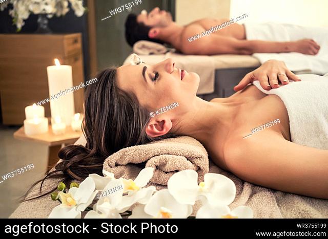 Young man relaxing with his partner on massage beds at modern spa and wellness center
