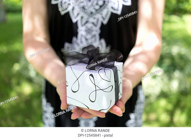 A woman holding a gift wrapped in black and white; Chilliwack, British Columbia, Canada