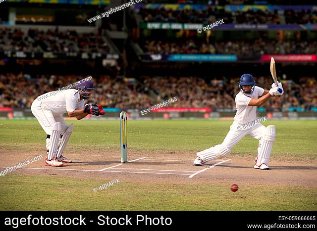 Cricketer batsman hitting a shot during a match on the pitch