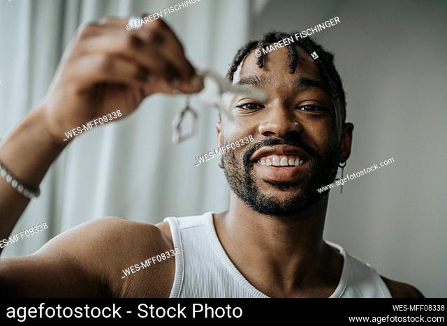 Smiling man with hair locs holding house key