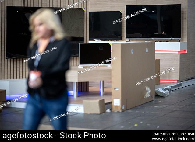 30 August 2023, Berlin: A woman walks past a stand with unpacked and unwrapped televisions outside the International Consumer Electronics Fair (IFA) at Messe...