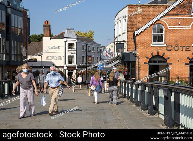 The Windsor and Eton bridge located between two towns with tourists and shoppers some wearing masks cross the bridge during Covid outbreak, Eton