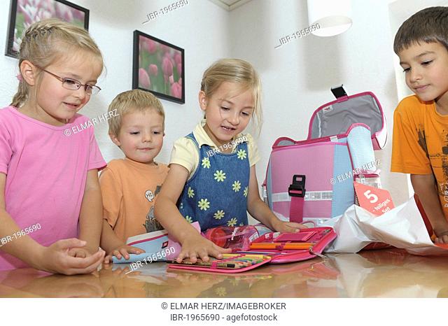 Girl, 6 years, has got new schoolbag and pencil case, other children are watching
