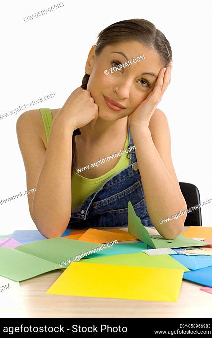 Young, beautiful woman sitting at desk over envelopes. Thinking of something, front view. White background