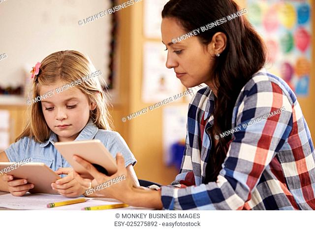 Elementary school teacher and pupil using tablet computers