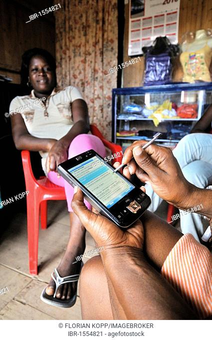 Social worker collecting data about the living situation of a poor Afro-Colombian family with a smartphone, Bajamar slum, Buenaventura, Valle del Cauca