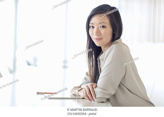 Portrait smiling businesswoman with digital tablet in conference room