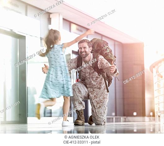 Daughter running and greeting soldier father in airport concourse