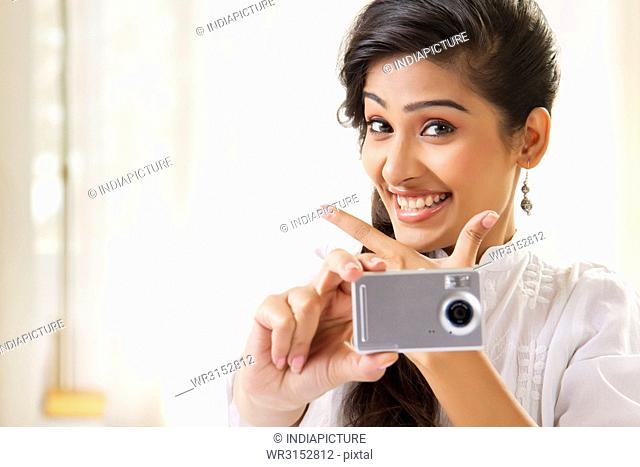 Young woman taking photograph with camera showing smiley face