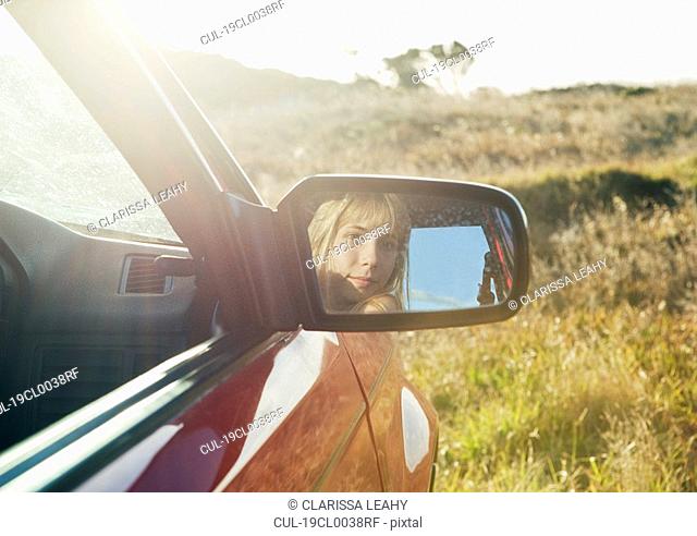 Girl looking in car mirror