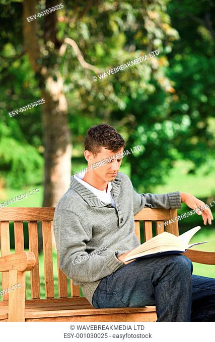 Young man reading his book on the bench