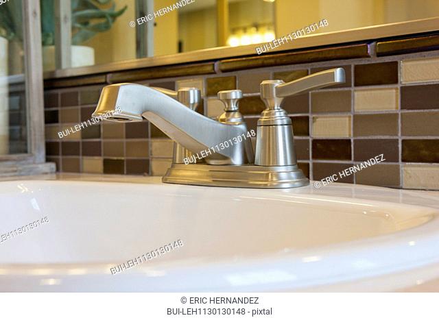 Faucet and spigots at bathroom sink with tiled backsplash
