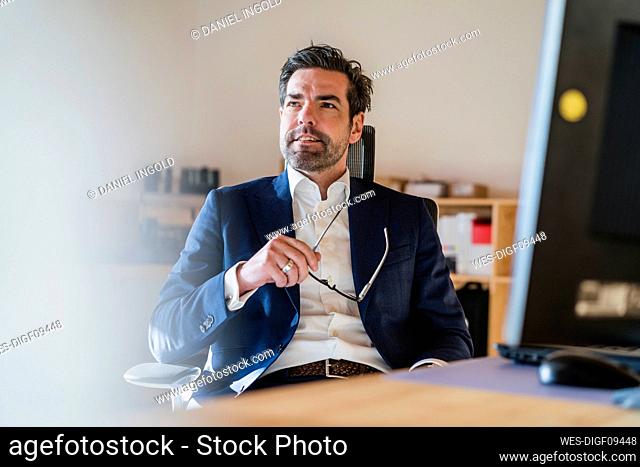 Portrait of businessman sitting at desk in wooden open-plan office