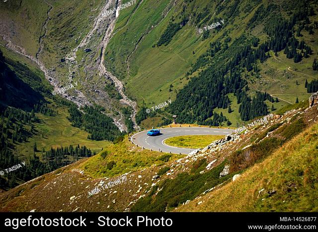 Austria, Salzburg, Carinthia, Hohe Tauern National Park, Grossglockner High Alpine Road, blue car driving a bend with the view into the valley