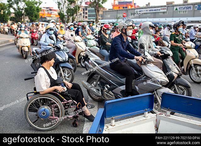 PRODUCTION - 26 September 2022, Vietnam, Hanoi: Hieu Luu (front) is on the road during rush hour, as are countless motor scooters