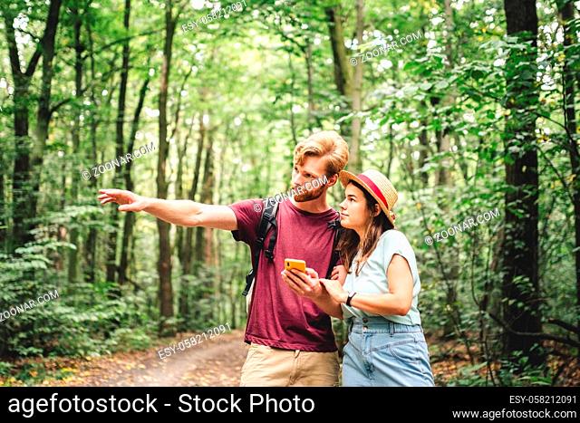 Couple hiking and using maps app on cell phone. Two people hikers looking at mobile phone trying find route. Hike in forest, looking smartphone