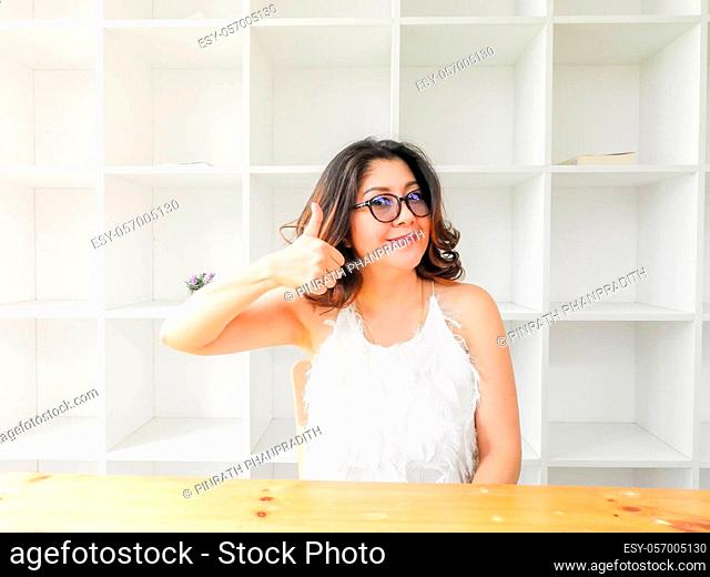 Beautiful woman smiling happy against white background with wood table and good attitude