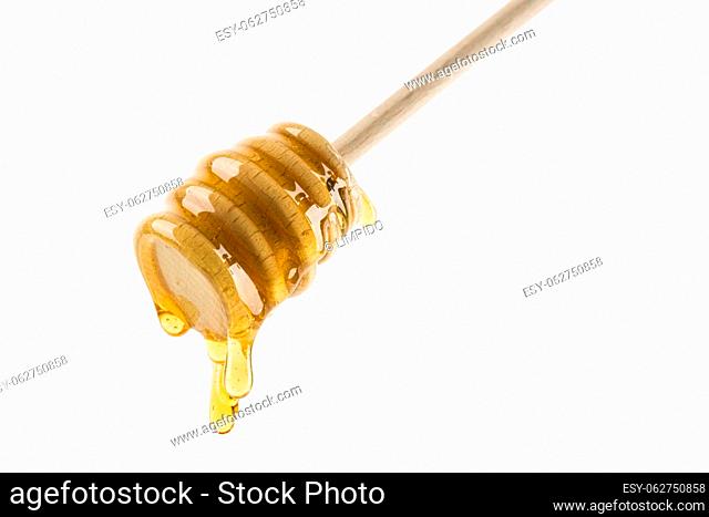 Honey dripping from wooden dipper, isolated on white