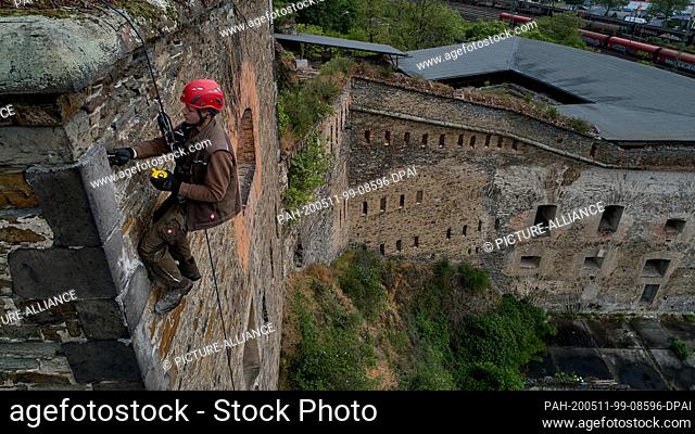 30 April 2020, Rhineland-Palatinate, Koblenz: An industrial climber attaches a reflector to the Franz fortress, part of the Koblenz major fortress
