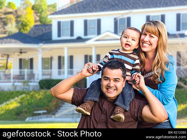 Happy mixed-race young family in front yard of beautiful house